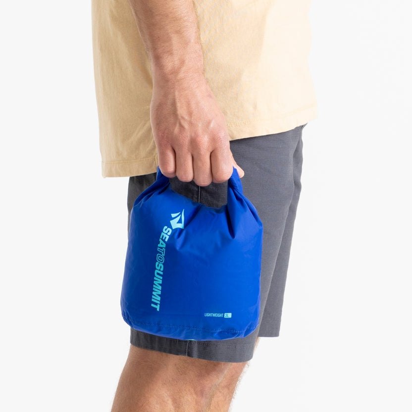 Sea to Summit Lightweight Dry Bag 3 litre in Surf Web Blue held in one hand to show its size.